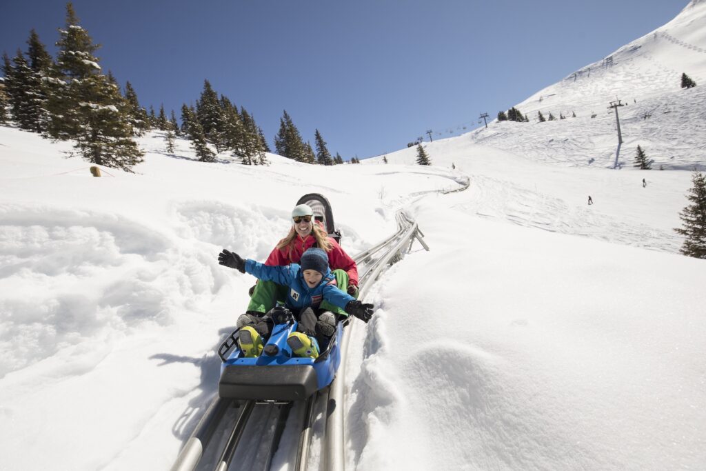 Mother and son going down rails among the snow.