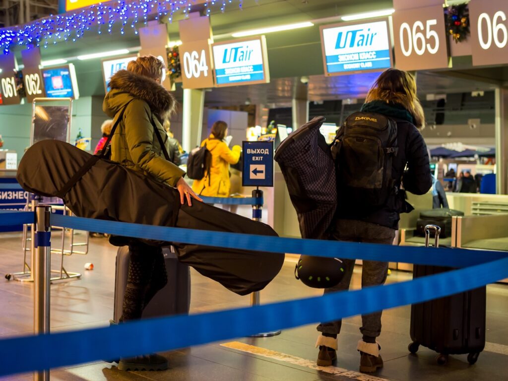 People queueing for airport check-in with ski and snowboard