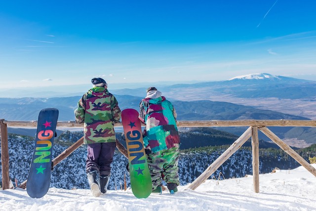 Two snowboarders looking out over the mountain in Borovets